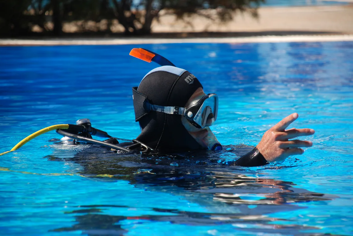A diver demonstrating hand signals in the pool