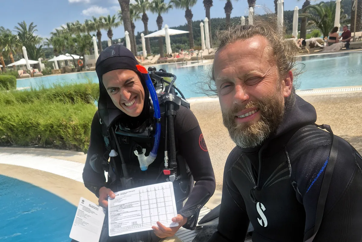 Divers reviewing training paperwork beside the pool