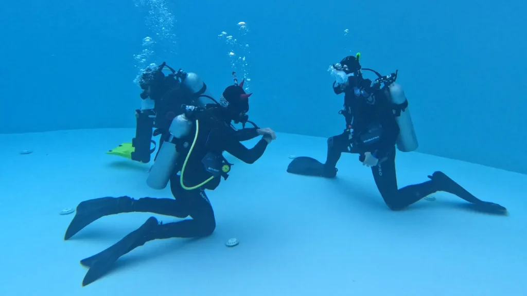 Scuba instructor demonstrating a skill to scuba divers underwater.