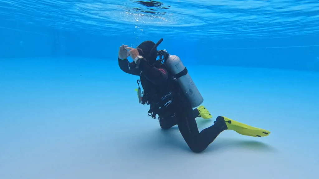 Scuba instructor demonstrating a skill to scuba divers underwater.